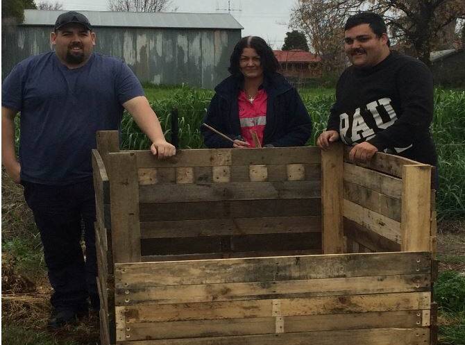 Proud of their handiwork: Some of the keen workers with the compost bin they constructed from old pallets. Photo: CONTRIBUTED
