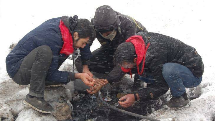 At a camp in Serbia, refugees wash hands outside in the snow. Photo: CARE/NSHC/Markovic