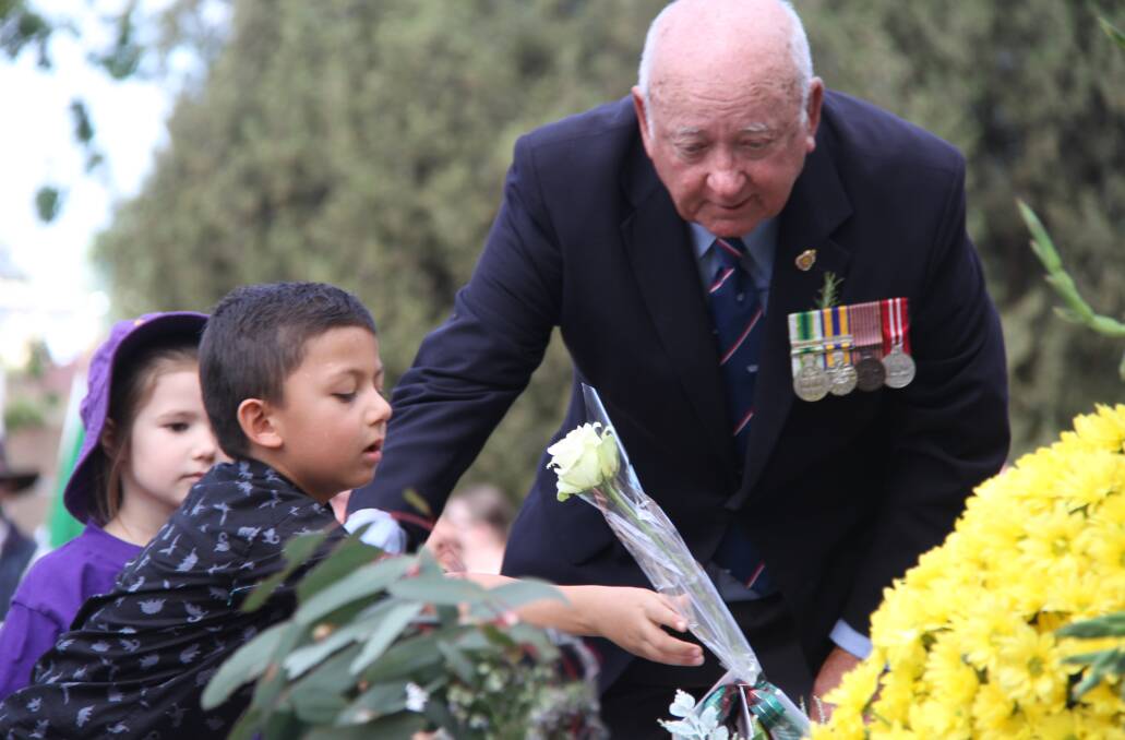 Wellington RSL sub branch president Peter Dowell helps a child during the service