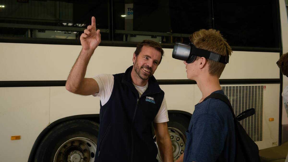 Tim Gentle explains to Laken Peacock, 15, Blackall, that he can look up, down, and all around him through the headset for a full 360 degree view. 