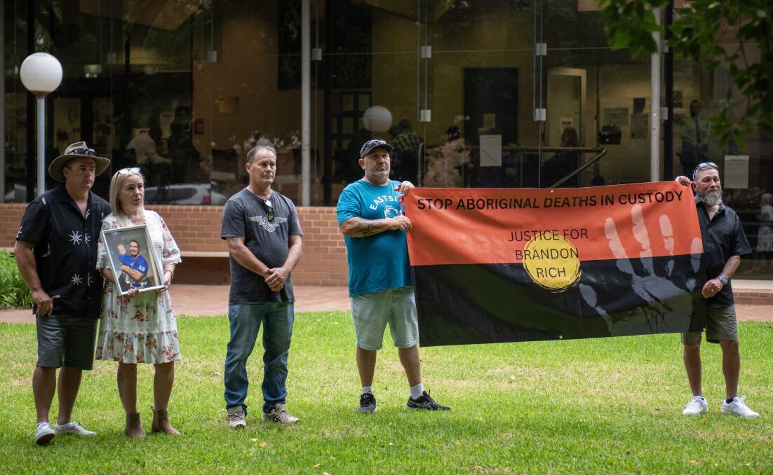 Brandon Rich's family outside Dubbo Court House holding up an Indigenous flag and his photo. Picture by Belinda Soole 