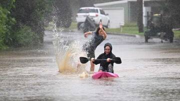 Children are seen on kayaks in floodwaters which have inundated the NSW town of Yarramalong on the Central Coast, north of Sydney. Photo: AAP Image/Jeremy Piper