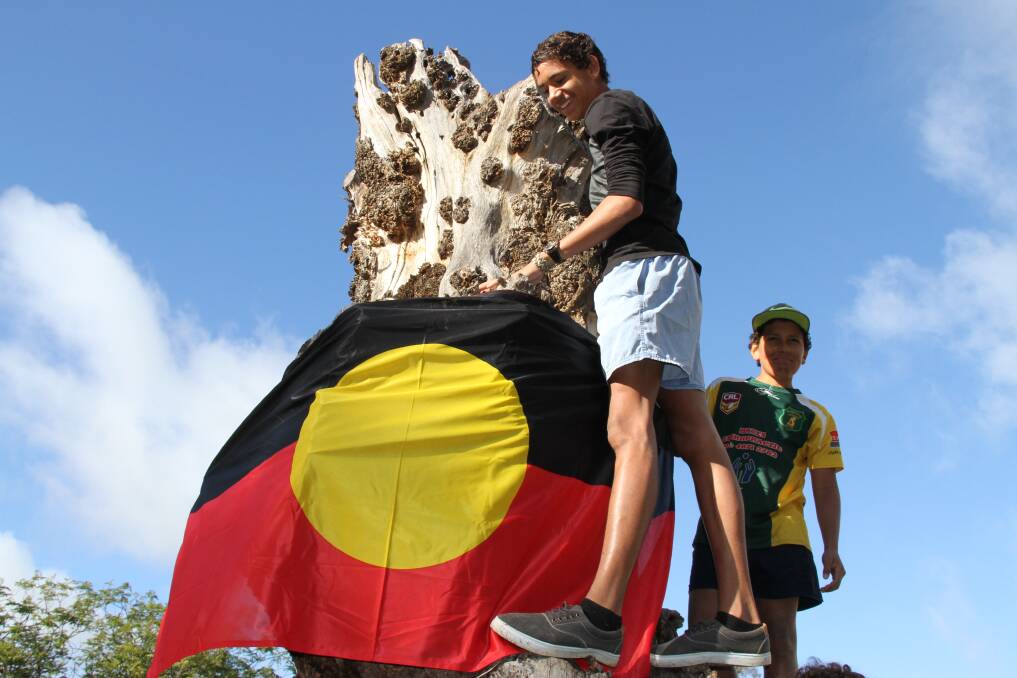 Maxwell Smith and Ezekiel Stanley putting the Aboriginal flag on the peppercorn tree which everyone remembered from their school days.