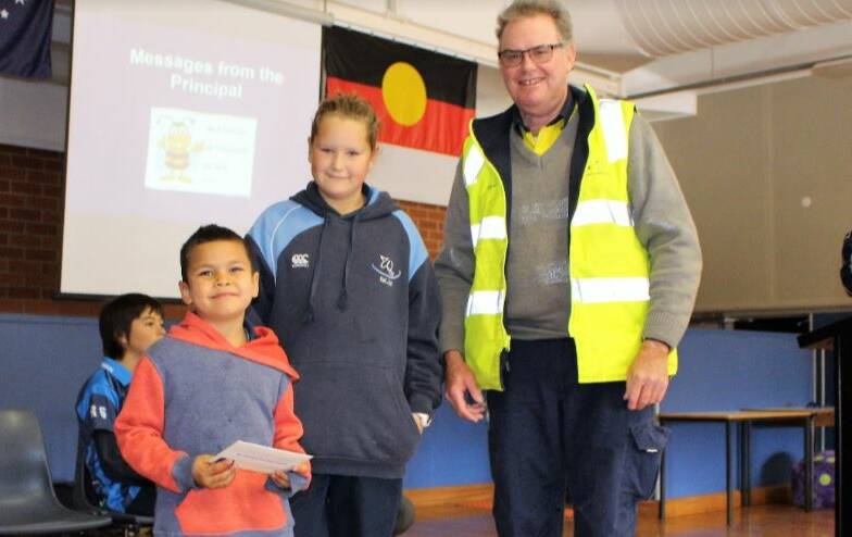 REASON TO CELEBRATE: Students Maddison Eade and Levi May, who help make the breakfasts every day, accepting he donation from Bodangora Wind Farm's Gavin Paul. Photo: CONTRIBUTED